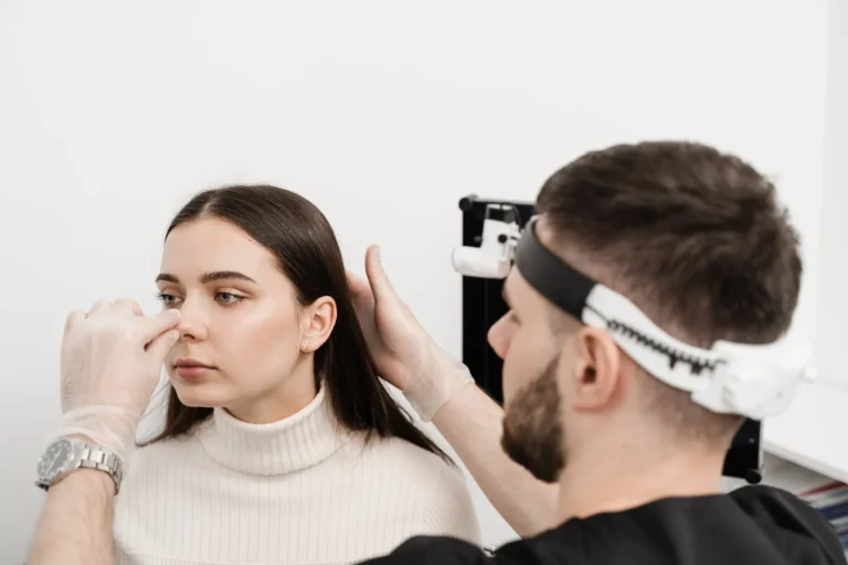 Surgeon examining a patient's nose during a pre-rhinoplasty consultation