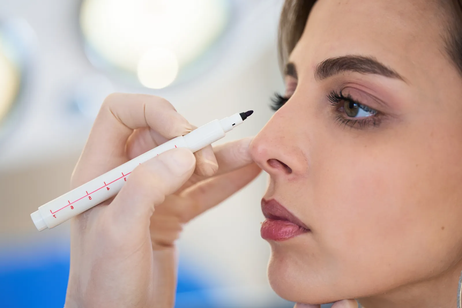 Plastic surgeon marking a patient's nose while planning rhinoplasty