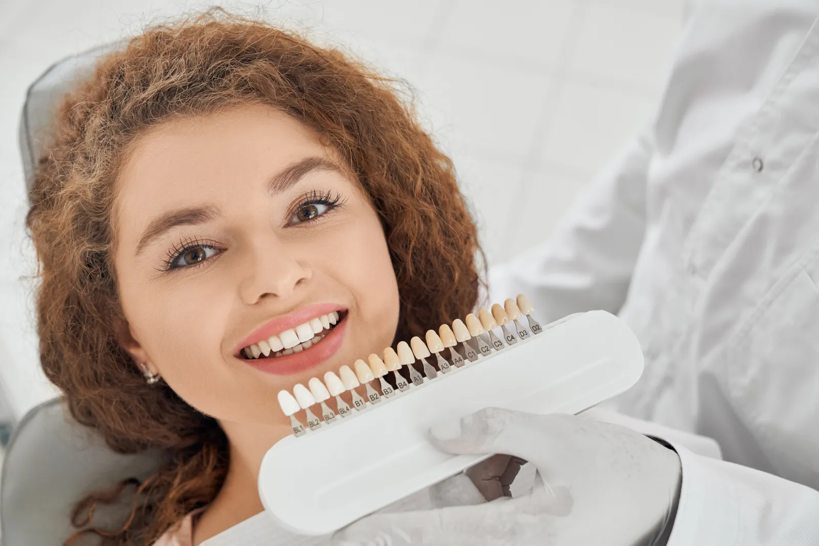Dentist matching tooth colour with a shade guide for veneers