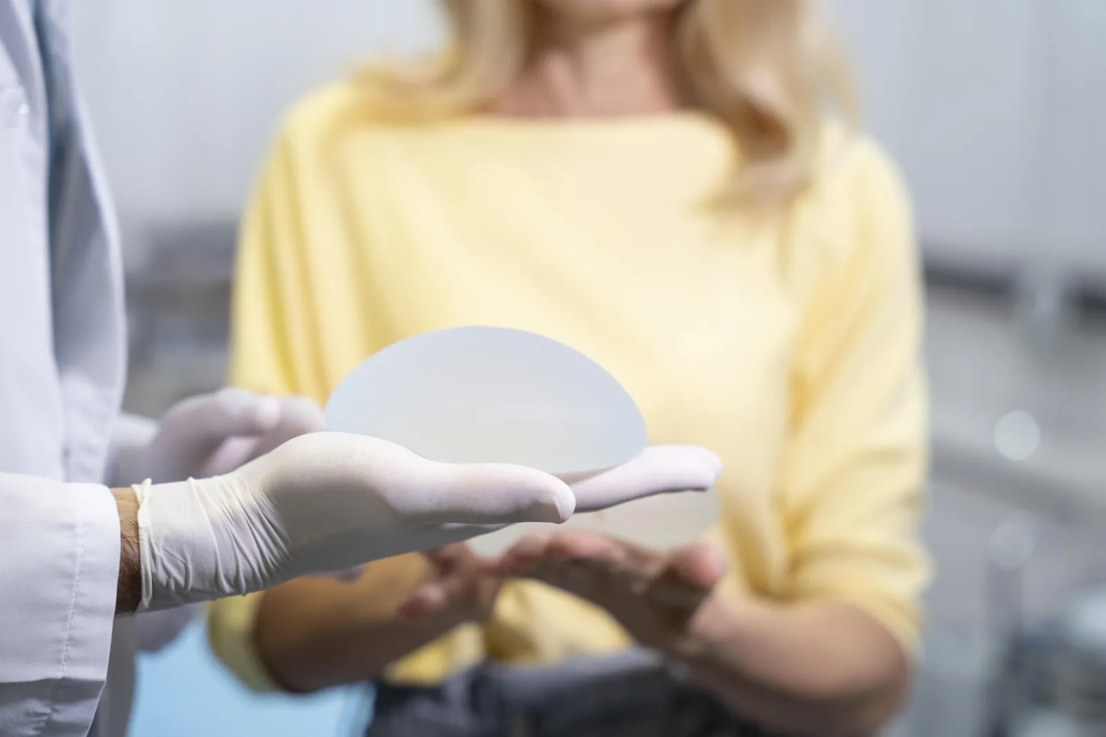 Doctor showing a silicone breast implant to a patient in consultation