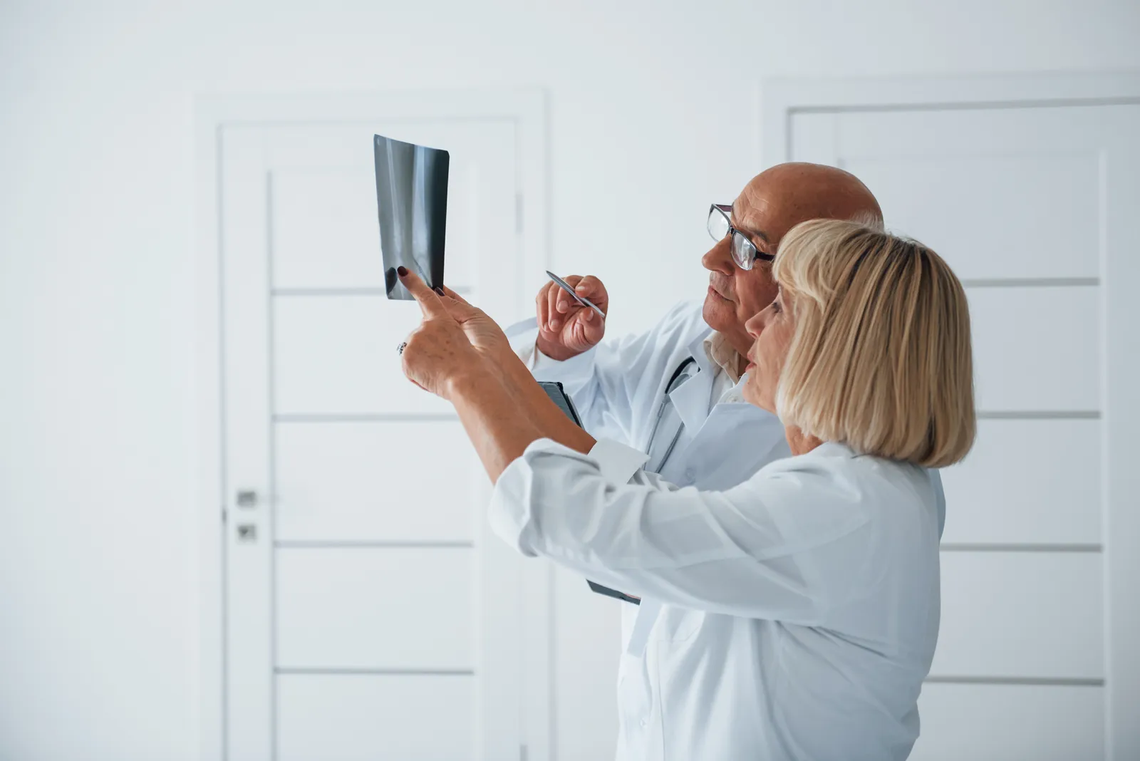 Two doctors review a leg X-ray together in a clinic
