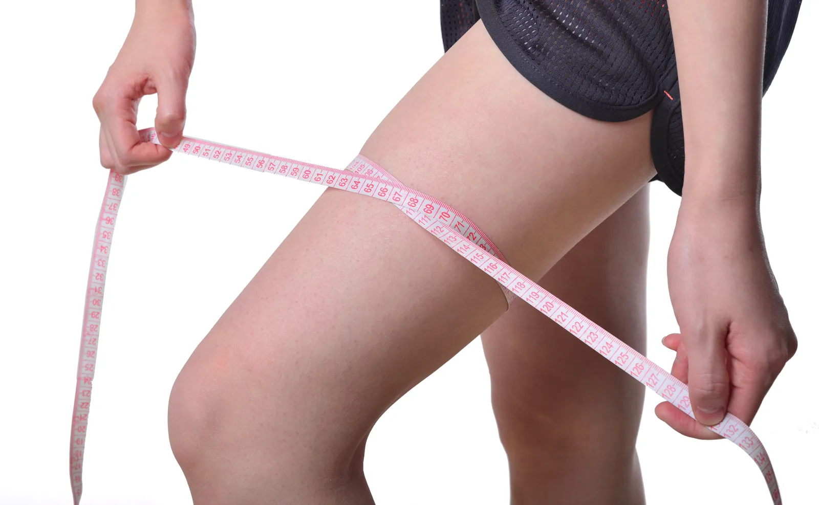 Woman measures her thigh circumference with a tape measure