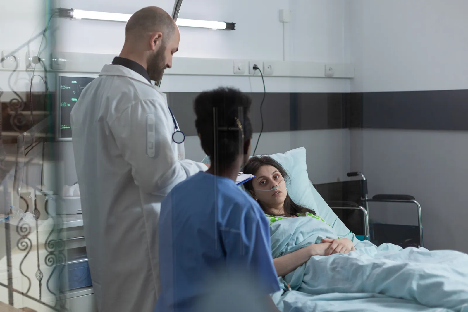 Doctor and nurse check on a recovering patient in bed